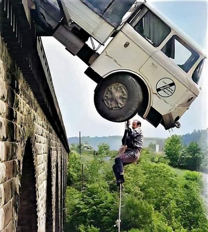 ein lkw hängt von einer brücke