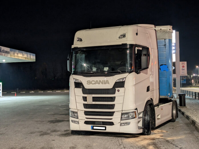 Ein weißer scania Lkw steht mit einem Defekt an einer Tankstelle 