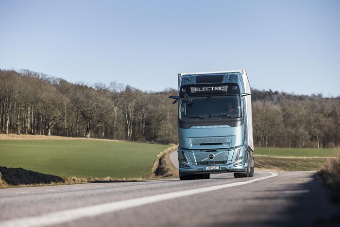 Volvo Trucks ist Marktführer für schwere Lkw in Europa. das bild zeigt einen lkw der marke volvo auf einer strasse zwischen wiese und bäumen.