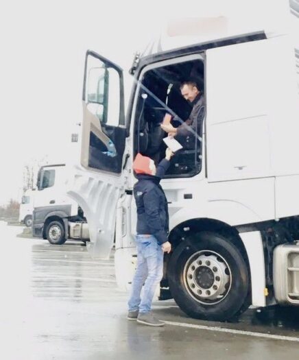 auf einem rasthof werden zu weihnachten geschenke an fahrer verteilt, die dort die feiertage verbringen müssen. im bild ist ein fahrer in einer weißen zugmachine zu sehen, der ein präsent entgegen nimmt.