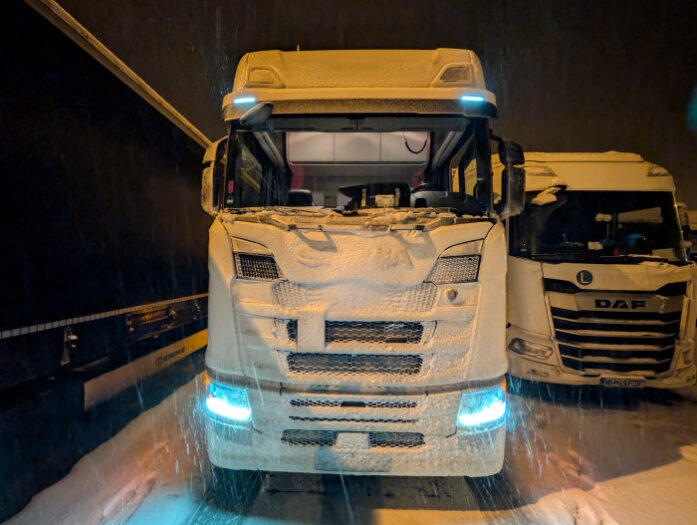 Ein Lkw scania steht verschneit auf einem Parkplatz an der Autobahn 