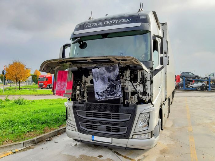 zu sehen ist ein lkw volvo auf einem rasthof in italien, dessen fahrer seine wäsche am kühlergrill trocknet